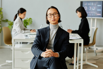 Minimal portrait of elegant Asian businessman looking at camera while posing professionally in office, copy space