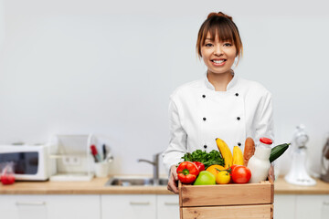 cooking, culinary and people concept - happy smiling female chef in toque holding food in wooden box over restaurant kitchen background