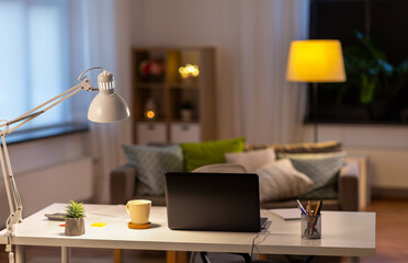 business, remote job and interior concept - close up of laptop computer, mug and pens on table at home office