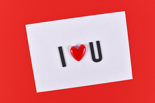 Valentine's day text 'I love you' spelled out with heart on white card on red background