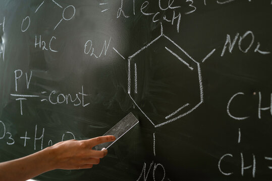 teacher of chemistry against blackboard explane chemical formula