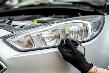 mechanic installing modern led H7 light bulb with wires in headlamp © RomanR