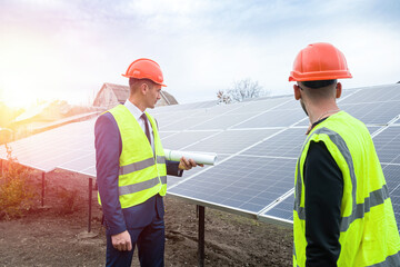 in men's clothing and helmets stand with a tablet standing near the newly solar panels.