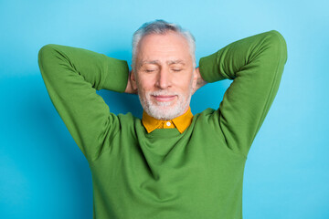 Fototapeta Photo of pretty dreamy retired man wear green sweater closed eyes arms behind head isolated blue color background obraz