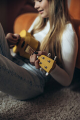 A teenage girl is learning to play the guitar, ukulele. High quality photo