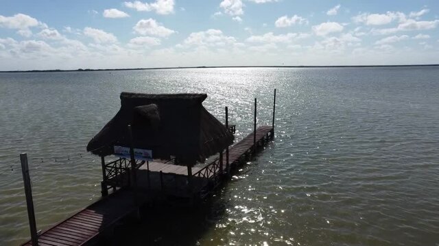 forward flight over wooden dock at lake blue sky and bird following chelem yucatan mexico