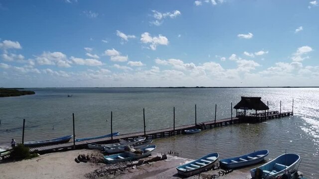 wooden dock and fishing boat at lake blue sky and chelem yucatan mexico