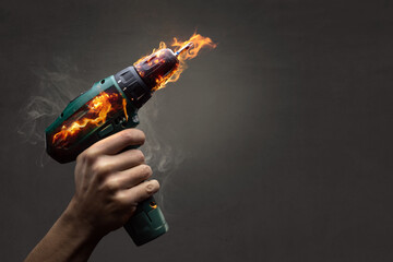 Hand holding a cordless screwdriver that is on fire