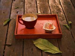 a hot fresh coffee on a red wooden tray