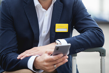 Close up of business man sitting on street with suitcase luggage and using a smartphone 