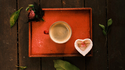 a hot fresh coffee on a red wooden tray