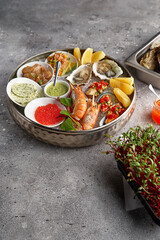 Metal tray with open oysters, raw mussels and caviar. Seafood assortment. On a stone background....