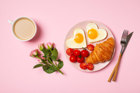 Healthy breakfast with eggs hearts and cup of coffee on pink background