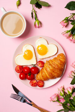 Healthy breakfast with eggs hearts and cup of coffee on pink background