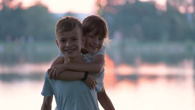 Happy siblings hugging lovingly in summer park. Young children brother and sister embracing each other outdoors. Family love and relationship concept