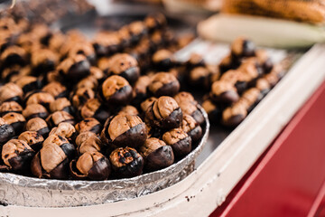 Roasted chestnuts on pan. Grilled chestnut snack food on the street market