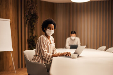Portrait of cheerful african-american woman wearing a mask, having fun at work.