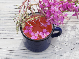 Herbal tea, chamerion angustifolium with pink flowers on a white wooden table. Useful plant...