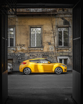 Tbilisi, Georgia - January 3, 2022: Yellow sports car on the old streets of the city - dissonance and discrepancy between times and cultures
