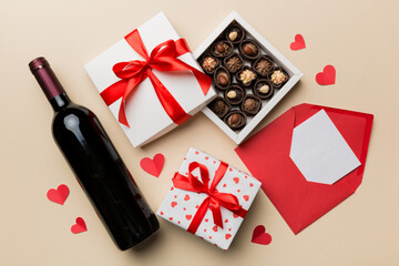 Bottle of red wine on colored background for Valentine Day with gift box, envelope and chocolate....