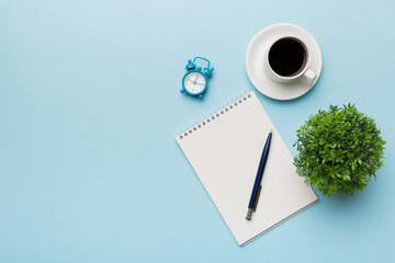 Modern office desk table with notebook and other supplies with cup of coffee. Blank notebook page for you design. Top view, flat lay