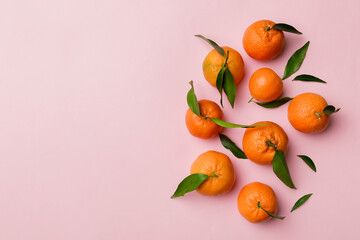 Many fresh ripe mandarin with green leaves on colored background, top view, space for text