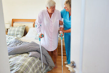 Altenpflegerin kümmert sich um Seniorin mit Krücken