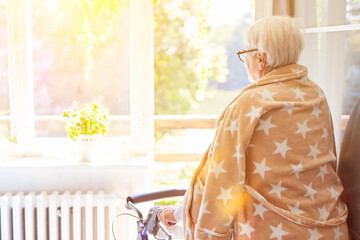 Alte Frau nach Schlaganfall mit Rollator im Bademantel