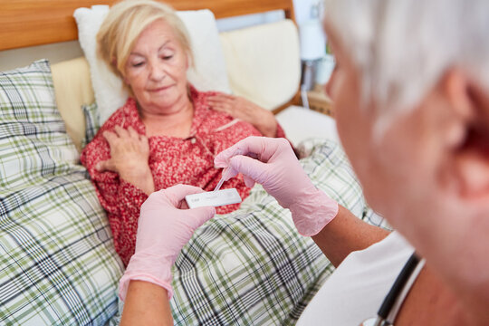 Ärztin macht CRP Test bei einer kranken Seniorin im Bett