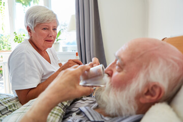 Obraz na płótnie Canvas Altenpflegerin hilft Senior beim Einnehmen von Tabletten