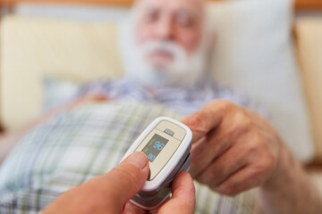 Krankenschwester misst Blutdruck am Finger vom Senior