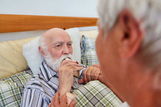 Altenpflegerin hilft Senior beim Inhalieren von Kortison Spray