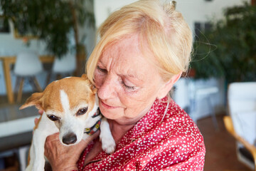 Seniorin kuschelt mit einem kleinen Hund als Haustier