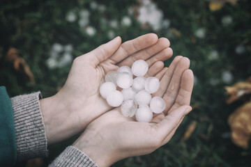 Woman holding hail grains after thunderstorm outdoors, closeup