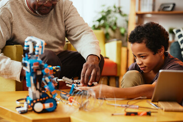 A grandad and grandson making a robot together at home. Education in robotics and electronics.