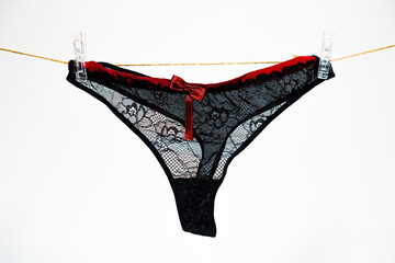 Black women's thong panties on a clothesline fastened with white pegs.