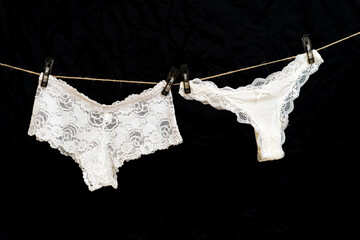 White women's thong panties on a clothesline fastened with white pegs.