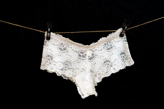 White women's thong panties on a clothesline fastened with white pegs.