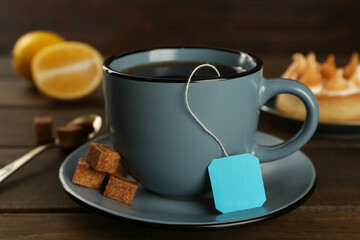 Tea bag in ceramic cup of hot water and sugar cubes