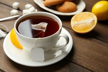 Tea bag in ceramic cup of hot water and lemon on wooden table