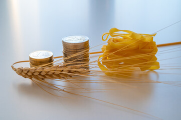 Ear of wheat, with pasta and coins next to it. Increase in the price of wheat, pasta and products.
