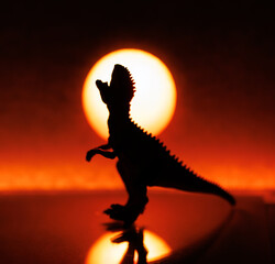 Silhouette of a dinosaur against the background of the sun. Dinosaur against the backdrop of sunset or sunrise. Ancient predatory prehistoric lizard. scary monster