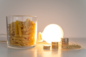 Ear of wheat, pasta, light bulb and coins, on white surface. Price of energy and wheat, which...