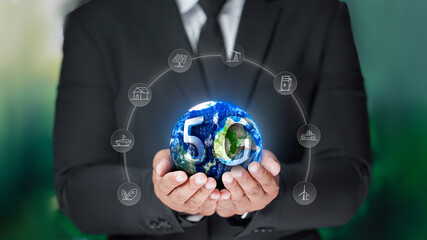 Businessman wearing a black suit with 5G digital letters on the earth and icons all around. internet of things on the background nature 5G Wireless Networking Elements of this image furnished by NASA
