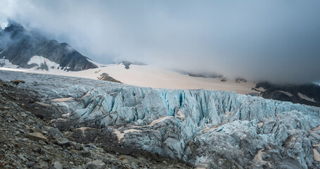 Fototapeta na wymiar Blue Ice Glacier du Tour flowing from Aiguille du Chardonnet mountain slopes with cloudy morning sky. Climate changing, global warming issues or wonders in Nature concept photo near Albert 1er refuge