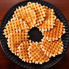 Belgian fables are laid out on a black plate in the shape of a ring. View from above.
