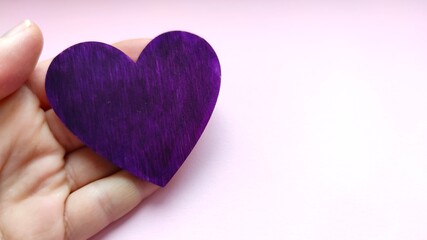 Hand holds a purple heart. Expression of understanding and compassionate love. Love and caring. The...