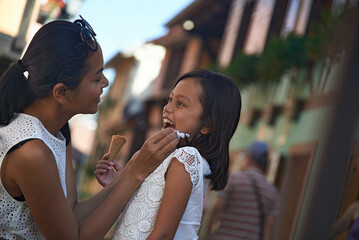 Asian mother wiping clean the face of her cute young daughter 