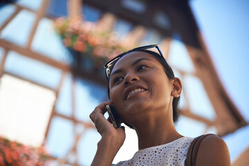 Asian woman talking on her mobile phone in summer sunshine