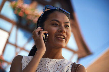 Asian woman talking on her mobile phone in summer sunshine